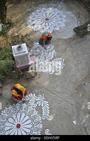 Agartala, Tripura, Inde, 12-01-2026 : des femmes peignent Alpona, sur le terrain avant le festival hindou Makar Sankranti dans le village de Lankamura à Agartala. Banque D'Images