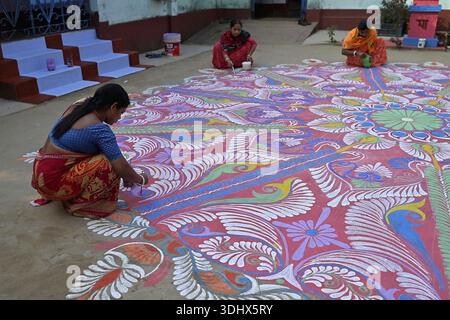 Agartala, Tripura, Inde, 12-01-2026 : des femmes peignent Alpona, sur le terrain avant le festival hindou Makar Sankranti dans le village de Lankamura à Agartala. Banque D'Images