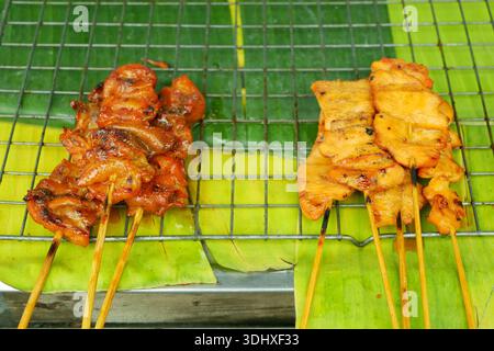 Brochettes de viande fournisseur de nourriture de rue affichant un assortiment de grillades comme des détails de peau de poulet cru en gros plan, coeur, gésier, foie et brochettes de viande de porc sur Banque D'Images