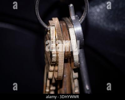 Vue macro gros plan de touches métalliques assorties sur un porte-clés avec une faible profondeur de champ, mettant en évidence la texture, l'usure et les détails métalliques Banque D'Images