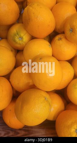 Cette photo en gros plan au-dessus du ciel présente un spectacle éclatant d'oranges fraîches. La composition se concentre sur la couleur vive et les surfaces texturées du frui Banque D'Images