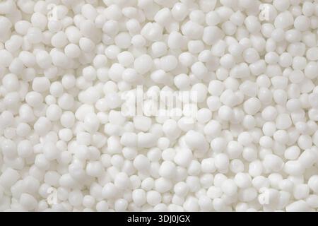 Une photo macro de haut en bas montre une collection dense et uniforme de granules de polymère, blanc brillant et avec une finition mate lisse. Banque D'Images