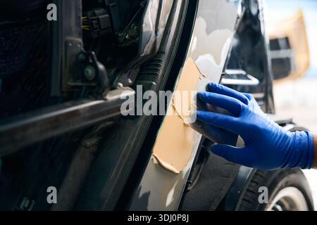 Réparateur utilisant du mastic à la voiture dans l'atelier de réparation automobile Banque D'Images