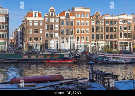 Maisons de canal hollandaises traditionnelles avec façades à pignons le long des Oudeschans à Amsterdam, avec des péniches et des reflets nautiques sur l'eau. Banque D'Images