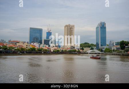 Une vue sur le fleuve Singapour vers Boat Quay montrant le développement de bâtiments de grande hauteur et de petites boutiques de pub de quai de bateau et de commerce de restaurant. Banque D'Images