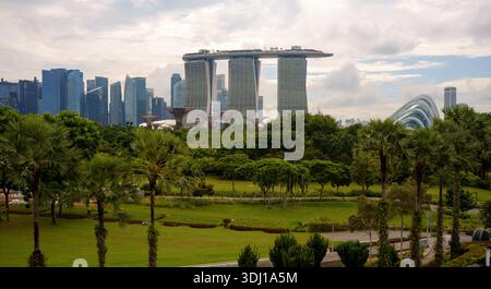 Une vue sur Marina Bay Sands et les gratte-ciel de Singapour central dans le cadre avec jardins par la baie au premier plan montrant les arbres verts et les champs Banque D'Images