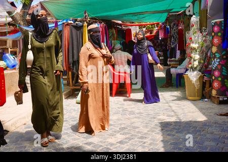 Femmes musulmanes en tenue traditionnelle marchant à travers le marché animé de Stone Town, Zanzibar Banque D'Images