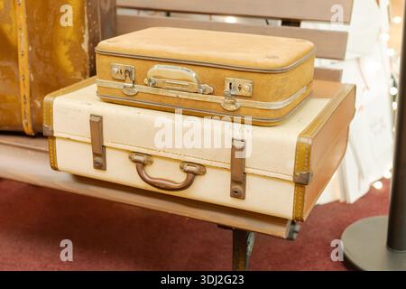 Deux valises vintage reposent sur un banc en bois. La valise du haut est petite et brune, tandis que celle du bas est plus grande et de couleur crème. Chute légère Banque D'Images