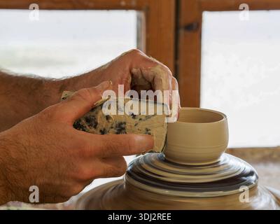 Mains façonnant bol en argile sur roue de poterie Banque D'Images