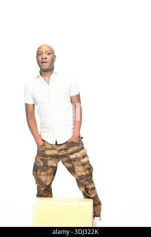 Portrait professionnel d'un jeune homme confiant portant une chemise blanche décontractée et un pantalon de camouflage de style militaire, éclairage lumineux, toile de fond blanche propre, Banque D'Images