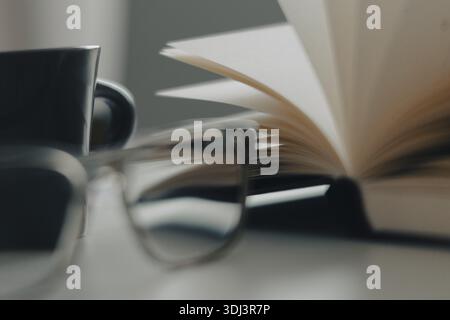 Blur montre des lunettes au premier plan, coupe et livre ouvert en arrière-plan, image symbolique pour la littérature et la lecture, Cologne, Rhénanie du Nord-Westphalie, Allemagne Banque D'Images