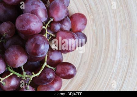Raisins rouges frais avec des gouttes d'eau dans un bol en bois Banque D'Images