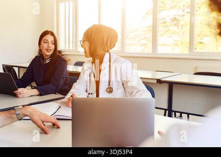 Séance de conseil d'étudiant en médecine avec le médecin en classe à l'aide d'un ordinateur portable et stéthoscope Banque D'Images