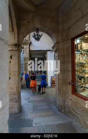 Espagne, Galice, Santiago, 15-28-2023, groupe de personnes marchent dans une ruelle étroite. Un chien marche avec l'une des personnes Banque D'Images