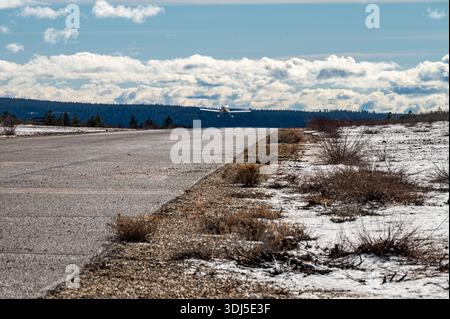Petit avion privé volant à basse altitude au-dessus d'une piste enneigée de montagne. Banque D'Images