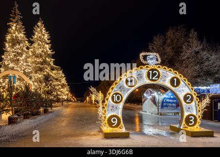 Oulianovsk, Russie - 14 février 2022 : énorme horloge de Noël de rue dans l'illumination du soir. Rue enneigée dans les décorations de Noël. Banque D'Images