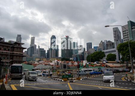 Une scène urbaine animée à Singapour avec des gratte-ciel modernes, un ciel nuageux et des rues animées avec des véhicules Banque D'Images