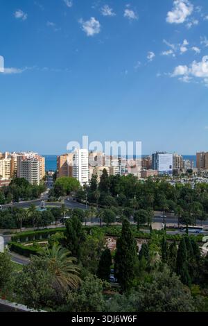 Une vue panoramique sur une ville côtière avec des bâtiments modernes, une végétation luxuriante et un ciel bleu clair Banque D'Images