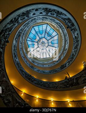 Vue sur un escalier en colimaçon à couper le souffle montant vers un puits de lumière octogonal lumineux, fusion de murs jaunes chauds et de verre bleu frais, Vatican CIT Banque D'Images