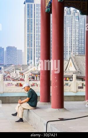 Homme assis au sommet de la Tour du tambour à Tianjin, Chine Banque D'Images