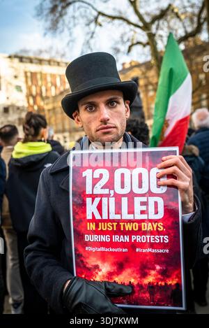 Homme tenant une pancarte à la veillée aux chandelles honorant les Iraniens tués en Iran et pour le changement de régime avec des photos de ceux qui ont perdu la vie, Lon Banque D'Images