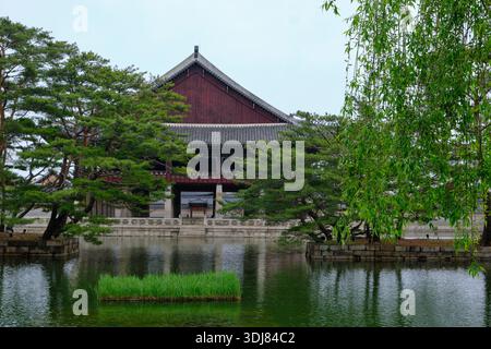 Séoul, Corée du Sud : Pavillon Gyeonghoeru au palais de Gyeongbokgung encadré de pins et de saules, reflété dans l'étang calme du palais Banque D'Images