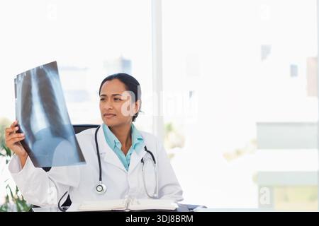 Médecin asiatique en blouse de laboratoire et stéthoscope tenant la radiographie thoracique et étudiant au bureau de la clinique. Médical, bureau, lumière du jour, lumineux, moderne, professe Banque D'Images