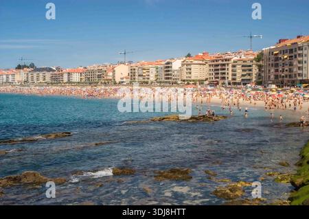 Espagne, Sanxenxo,08-02-2005 : une plage avec une grande foule de gens et un océan bleu. La scène est vivante et amusante Banque D'Images