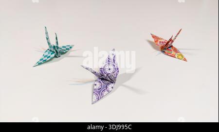 Trois grues en papier origami isolées sur fond blanc. Culture japonaise traditionnelle. Sculpture en papier par des techniques de pliage et de relaxation. Banque D'Images