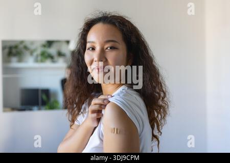 Jeune femme asiatique avec bandage adhésif sur le bras après vaccin contre le virus Corona. Premiers soins. Concept médical, pharmaceutique et de soins de santé. Banque D'Images