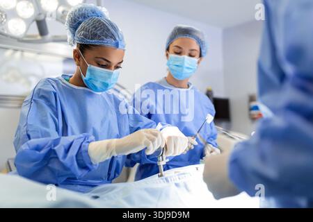 Chirurgienne concentré toute intervention chirurgicale avec son équipe en salle d'opération de l'hôpital. Les médecins au cours de l'intervention en salle d'opération. Banque D'Images