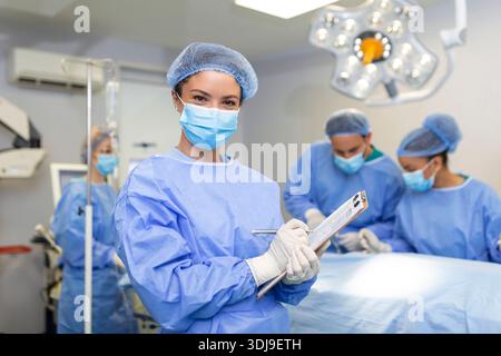 Portrait d'une belle femme médecin chirurgien mettant des gants médicaux debout dans la salle d'opération. Chirurgien au bloc opératoire moderne Banque D'Images