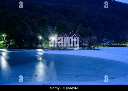 Lac gelé Golcuk à Bolu, Turquie : paysage naturel hivernal avec emblématique maison de montagne en bois, forêt de pins verts et réflexion calme pour Welln Banque D'Images