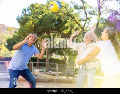 Club social de joyeux personnes âgées diverses appréciant le volley-ball le jour ensoleillé d'octobre plein air Banque D'Images
