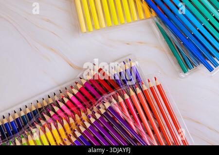Les crayons de couleur en paquets affichent diverses teintes, alignées sur la surface légère, prêtes pour des projets artistiques. Banque D'Images