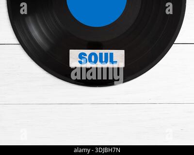 Disque vinyle avec une tuile indiquant le genre musical soul reposant sur un fond de bois blanc, représentant le concept de musique et ses genres Banque D'Images