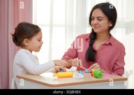 Mère et fille appréciant le temps d'apprentissage créatif avec de l'argile à modeler à la maison Banque D'Images