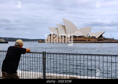 Sydney, Australie. 26 janvier 2026. Un homme est vu regarder l'Opéra de Sydney en attendant le feu d'artifice de l'Australia Day. Les gens se rassemblent au Circular Quay Harbour Lookout en attendant le feu d'artifice de l'Australia Day, alors que la foule s'accumule le long du port de Sydney avant les célébrations de la soirée. (Photo de Ye Myo Khant/SOPA images/Sipa USA) crédit : Sipa USA/Alamy Live News Banque D'Images