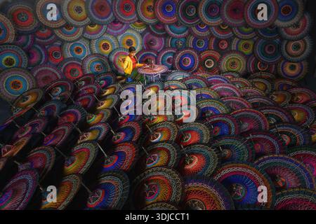 Jeune femme birmane assise sur un tabouret dans un atelier fabriquant des parapluies Pathein colorés traditionnels (Pathein hti), Myanmar Banque D'Images