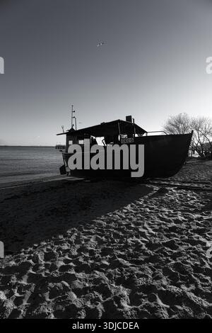 Une photographie en noir et blanc saisissante capture un vieux bateau de pêche, ORE-6, reposant sur une plage de sable. La lumière puissante et à contraste élevé projette des images spectaculaires Banque D'Images