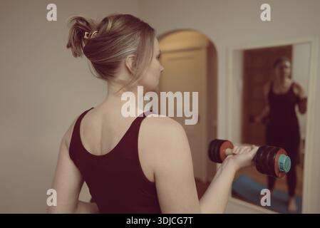 Femme sportive faisant des boucles de biceps avec haltère. Banque D'Images