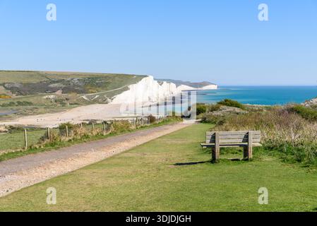 Banc en bois vide le long d'un chemin désert offrant une vue magnifique sur les falaises de Seven Sisters sur la côte sud de l'Angleterre par un jour de printemps ensoleillé Banque D'Images