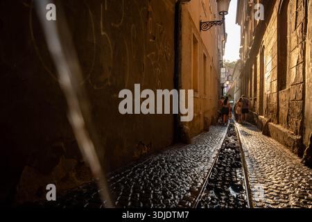 Ljubljana, Slovénie - 10 août 2025 : la lumière du soleil brille sur les anciens pavés humides d'une ruelle étroite de Ljubljana tandis que les piétons marchent vers le Banque D'Images