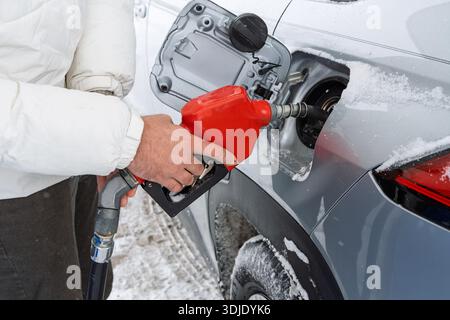 Gros plan d'un homme qui fait le plein de sa voiture à une station-service. L'image capture l'action d'insérer la buse de carburant dans le réservoir d'essence de la voiture horizontalement Banque D'Images