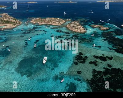Vue aérienne de yachts dispersés dans les eaux turquoises autour des îles rocheuses, Maddalena, Sardaigne, Italie. Banque D'Images
