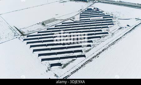 La vue aérienne des panneaux solaires contraste fortement avec la vaste étendue de champs enneigés, soulignant le mélange de technologie et de nature, Sremska Banque D'Images
