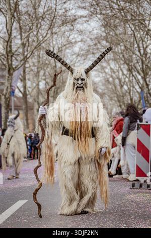 Zug, Suisse - 1er mars 2025 : une personne en costume de bête à fourrure Tschaggatta avec un masque en bois à cornes lors d'un défilé Fasnacht du carnaval d'hiver suisse Banque D'Images