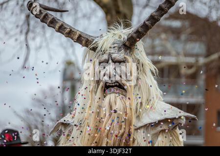 Zug, Suisse - 1er mars 2025 : une personne en costume de bête à fourrure Tschaggatta avec un masque en bois à cornes lors d'un défilé Fasnacht du carnaval d'hiver suisse Banque D'Images