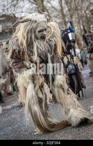Zug, Suisse - 1er mars 2025 : une personne en costume de bête à fourrure Tschaggatta avec un masque en bois à cornes lors d'un défilé Fasnacht du carnaval d'hiver suisse Banque D'Images