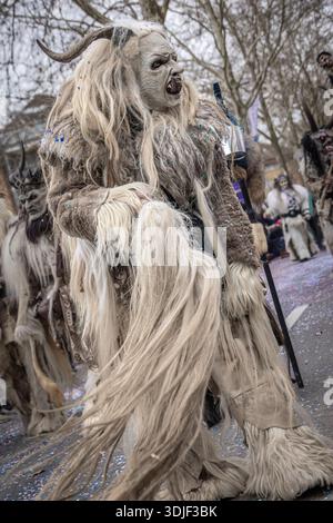 Zug, Suisse - 1er mars 2025 : une personne en costume de bête à fourrure Tschaggatta avec un masque en bois à cornes lors d'un défilé Fasnacht du carnaval d'hiver suisse Banque D'Images